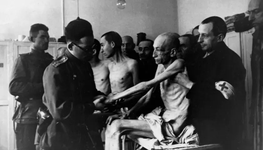 Wstrząsający obraz ofiar obozu koncentracyjnego, ukazujący skrajne wycieńczenie. To wizualna definicja holocaustu.