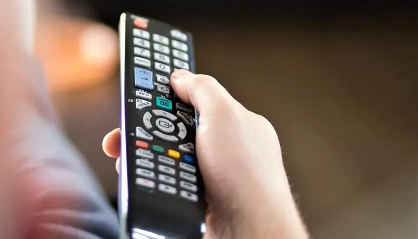 Dłoń trzyma pilot, zastanawiając się, czy telewizję naziemną można oglądać przez internet.