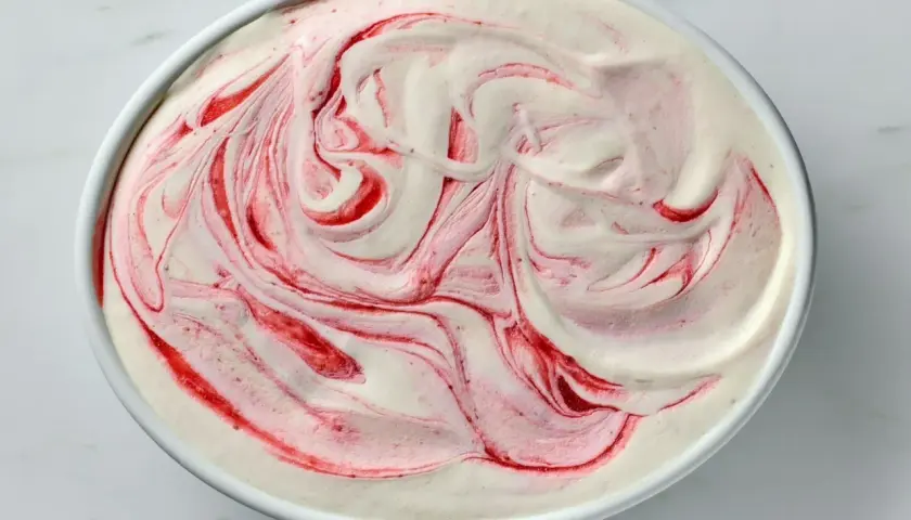 Kremowe lody jogurtowe z malinową spiralką, wyglądające jak dzieło sztuki.