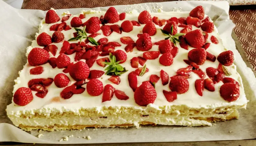 Un délicieux entremet fraise, garni de fruits rouges frais et de feuilles de menthe, sur une base crémeuse.