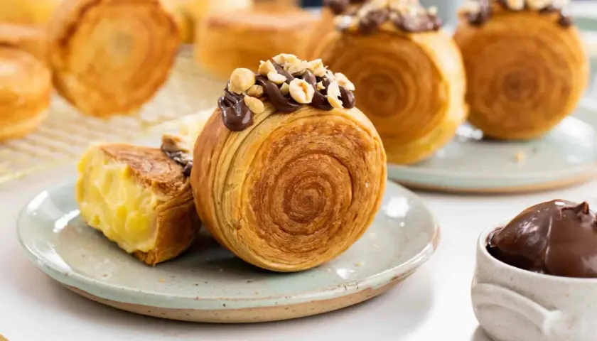 Deliziosi dolci francesi, croissant a spirale ripieni di crema e guarniti con cioccolato e nocciole.