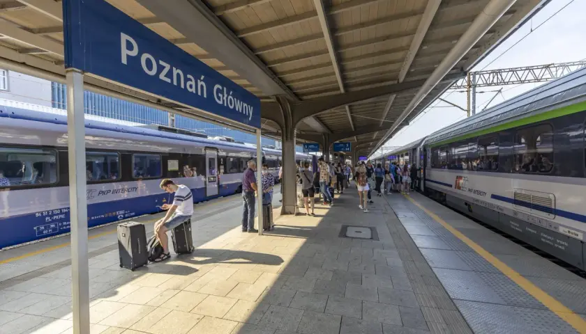 Peron na dworcu Poznań Główny z pociągami i pasażerami.