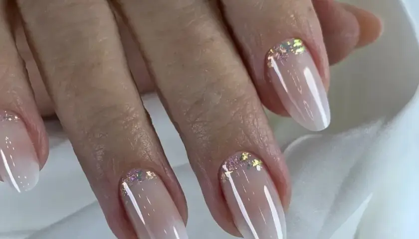 Elegancki manicure baby boomer z subtelnymi drobinkami brokatu na paznokciach.