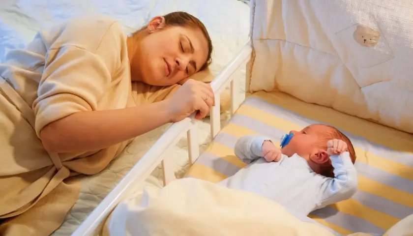 Mamma dorme accanto al lettino dove un bambino di 2 anni si sveglia piangendo disperato.