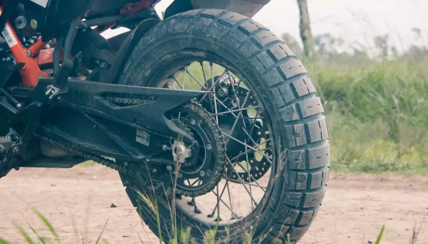 Tylne koło motocykla z oponą Pirelli Scorpion Rally STR na szutrowej drodze, gotowe na przygodę.