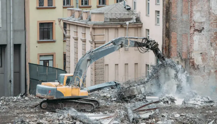 Koparka niszczy budynek do rozbiórki. Co z lokatorami? Gruz i pył unoszą się w powietrzu.