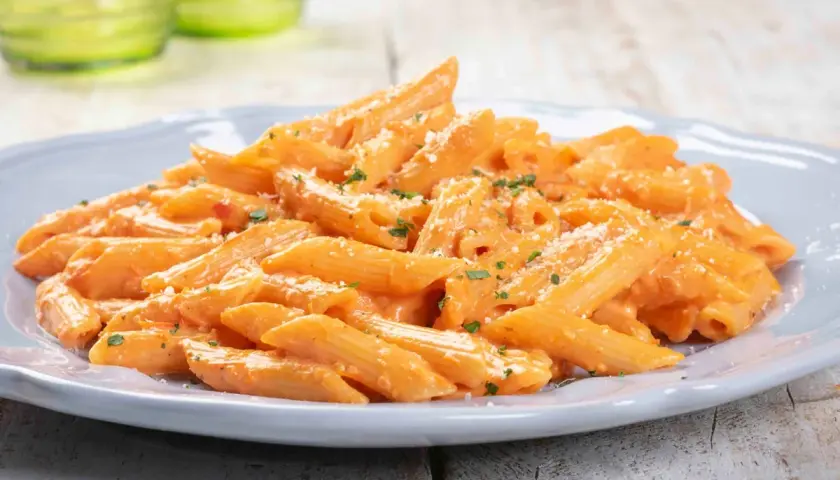 Penne cremose con salsa rosa, un piatto gustoso e paste facili da fare, guarnito con parmigiano e prezzemolo.