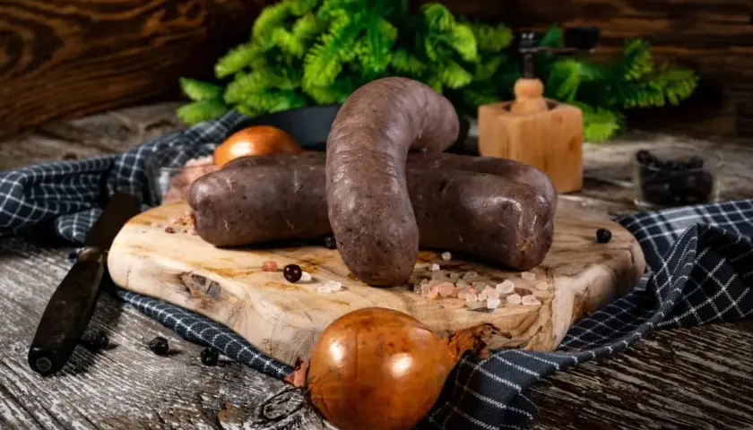 Kaszanka na desce z cebulą i przyprawami. Zastanawiasz się, czy kaszankę można mrozić? Tak, można ją mrozić.