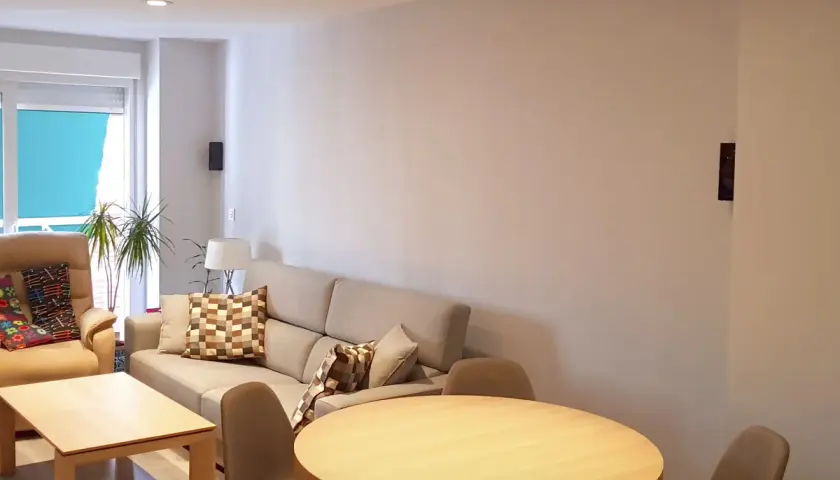 Salón moderno con sofá beige, mesa de centro y mesa redonda. El **IP40 significado** se refleja en la iluminación empotrada y el diseño funcional.
