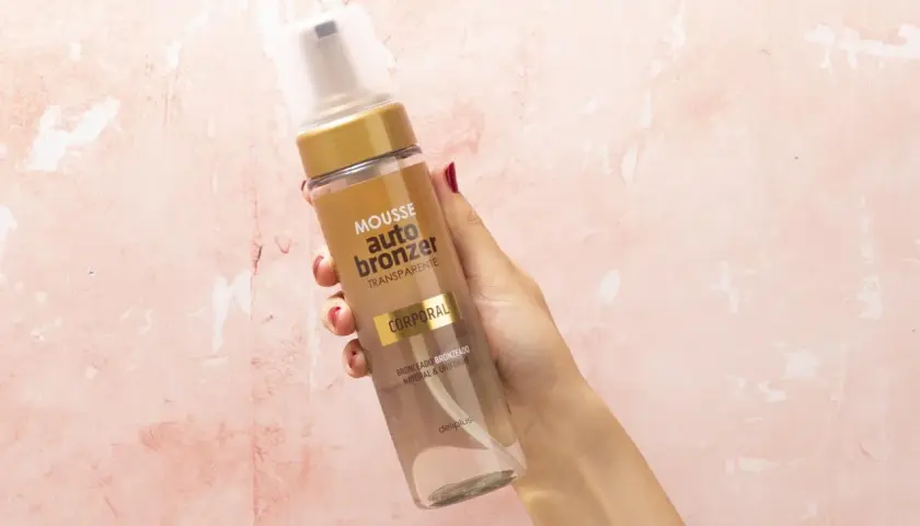 Mano sostiene botella de mousse autobronceador Deliplus de Mercadona. Bronceado natural y uniforme.