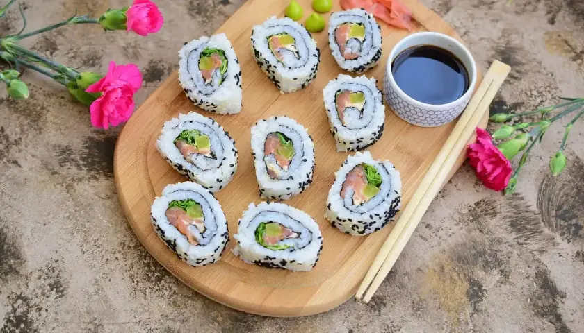 California sushi z łososiem i awokado, posypane czarnym sezamem, podane z sosem sojowym i wasabi.