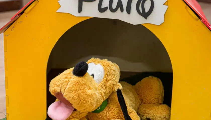 Pluszowy piesek Pluto, jeden z ulubionych bohaterów z bajek, leży w swojej żółtej budzie.