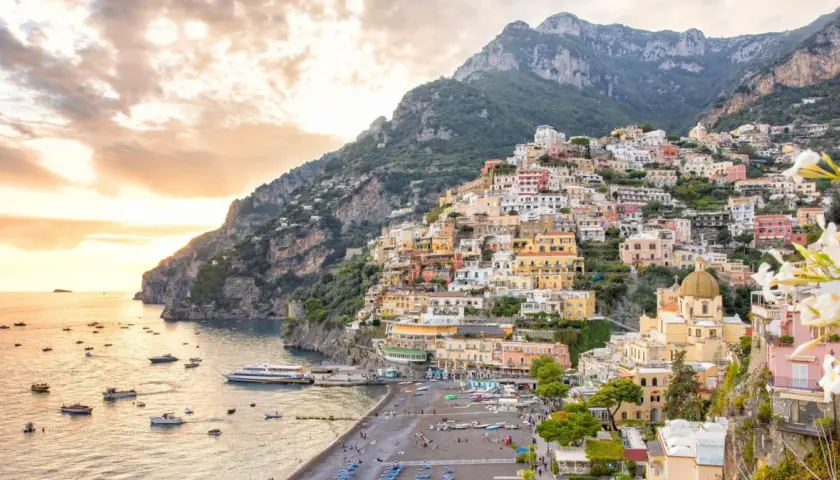 A stunning view of Positano, perfect for your Amalfi Coast 2-day itinerary. Colorful houses cascade down a steep cliff to a beach dotted with boats.