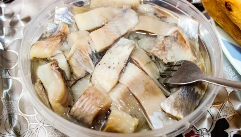 Pyszne śledzie na wielkanoc w zalewie, gotowe do podania. Widoczna jest też część bagietki.