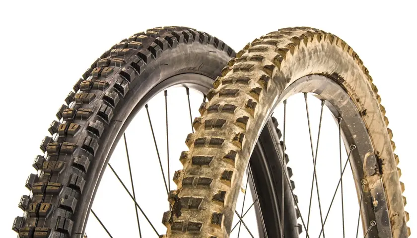 Two mountain bike tires, one new and one worn, illustrate when to replace mountain bike tires.