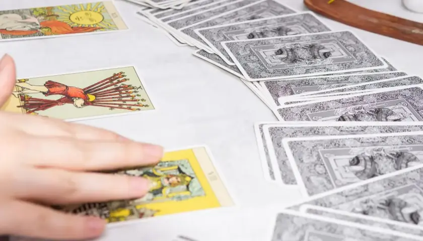 Tarot tygodniowy Skorpion: rozłożone karty tarota, ręka wybiera jedną z nich.