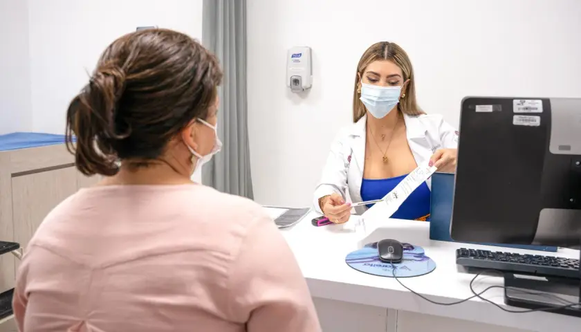 Médica explica tratamiento para la acidez en la boca a paciente.