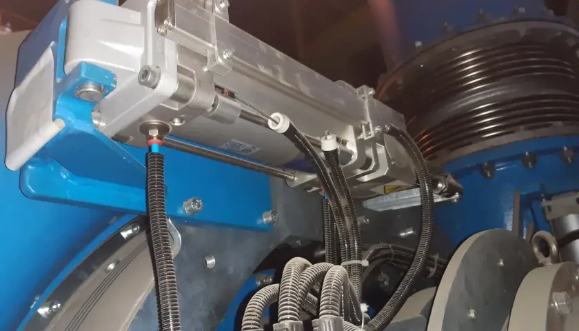 Szczegółowy widok mechanizmu z napędami pneumatycznymi, przewodami i elementami montażowymi.
