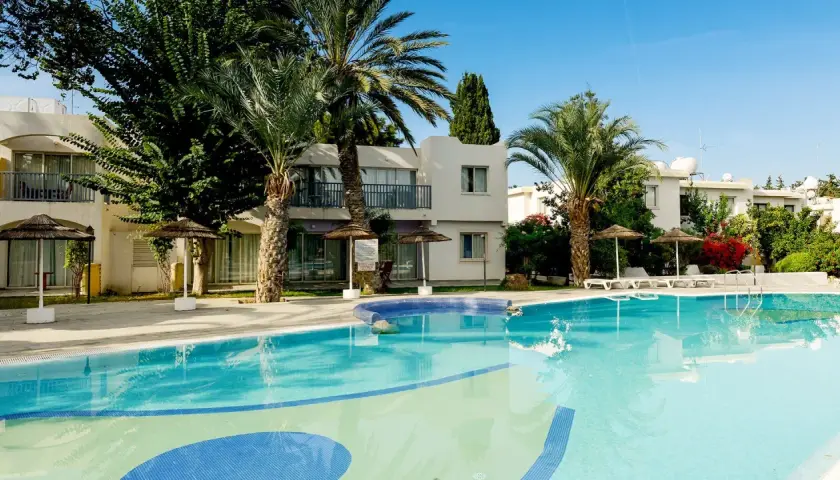 Basen w hotelu Leptos Paphos Gardens Holiday Resort, otoczony palmami i zielenią, zaprasza na relaks.