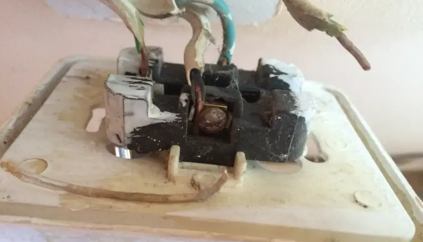 Widok wnętrza gniazdka elektrycznego, pokazujący przewody. Dowiedz się, jak sprawdzić uziemienie w gniazdku miernikiem.