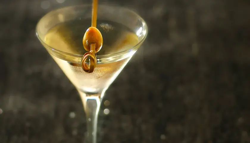Un verre à martini rempli d'un cocktail clair, garni d'une olive sur un cure-dent. Une image parfaite pour une vodka martini recette.