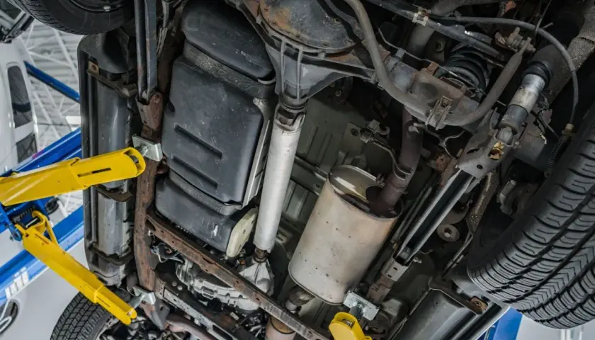 Podnośnik samochodowy podtrzymuje auto, ukazując podwozie z układem wydechowym i zbiornikiem paliwa. Czas na wypalanie DPF.