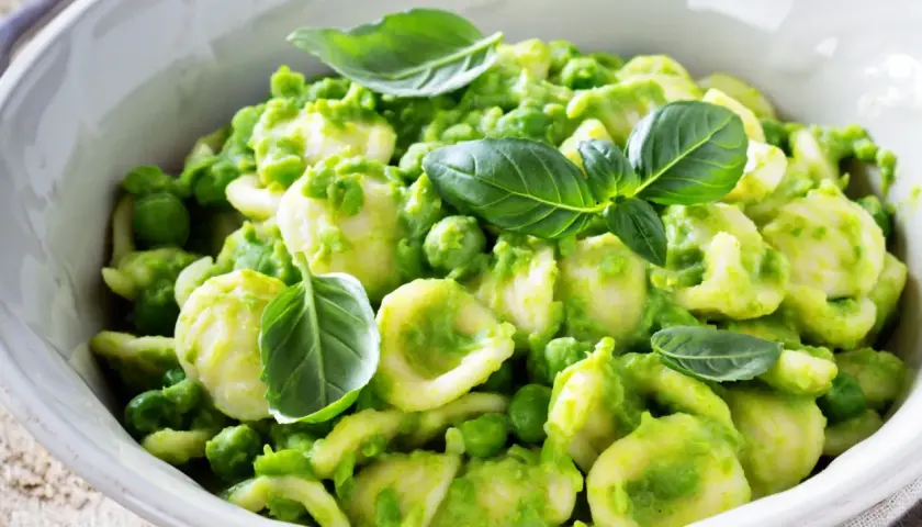 Orecchiette fatte in casa con crema di piselli e basilico fresco, un piatto primaverile invitante.