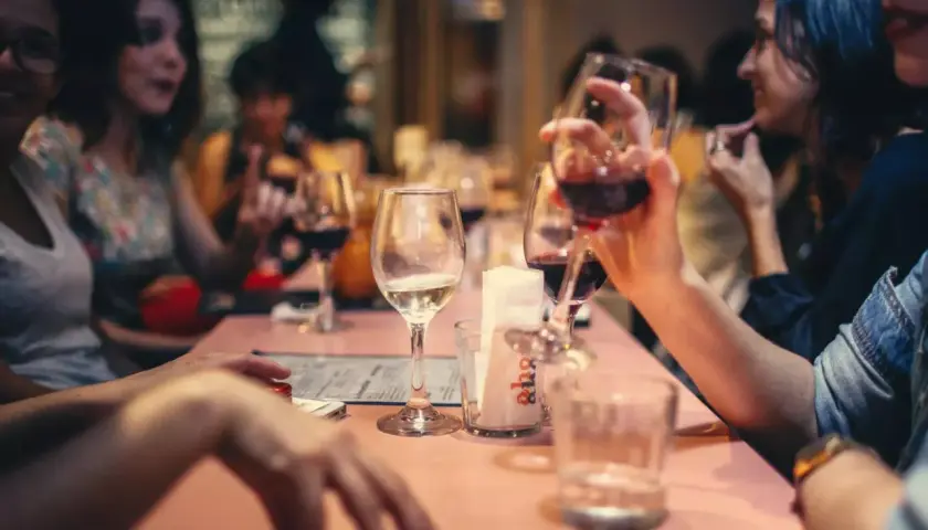 Amis partageant un bon type vin rouge et blanc autour d'une table rose.