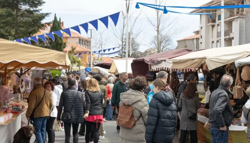 Gente paseando por el mercadillo de Noja, con puestos de artesanía y decoración bajo toldos.