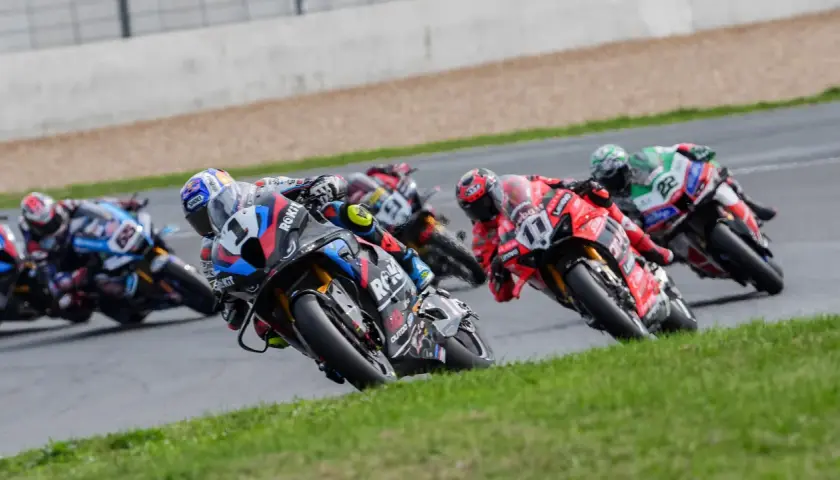 Pilotos de superbikes compiten en una carrera, inclinándose en una curva. ¡Emoción pura donde ver superbikes!