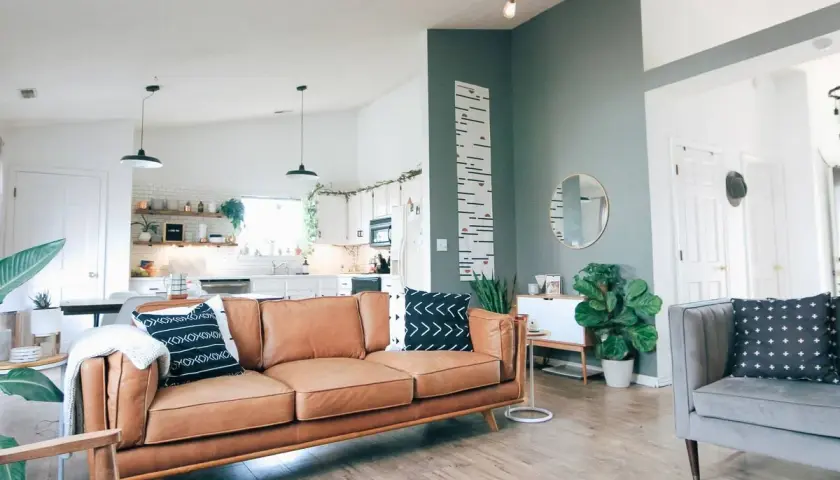 Sofá de cuero marrón y cojines con patrones en azul y verde combinan perfectamente en este salón moderno.
