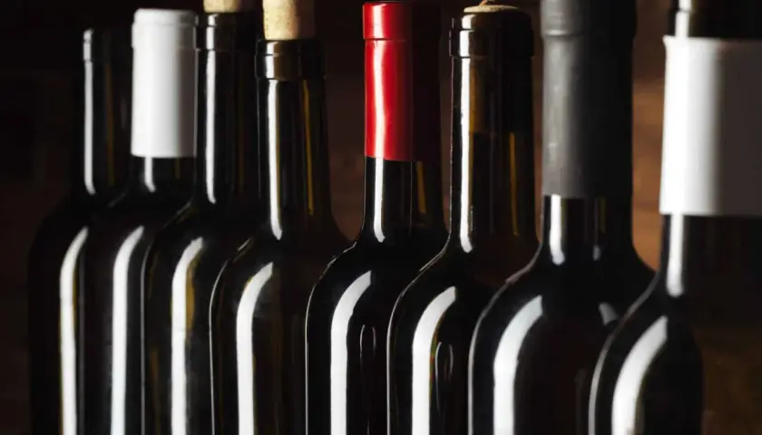 Bouteilles de vin alignées, certaines avec bouchons en liège, d'autres avec capsules. Un aperçu des trésors d'un domaine viticole Roussillon.