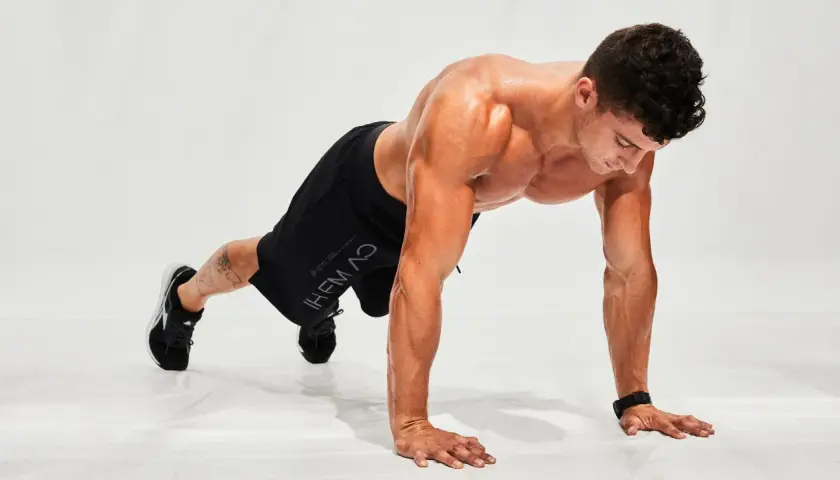 Hombre haciendo flexiones en posición de plancha, listo para un entrenamiento de **hiit en casa**.