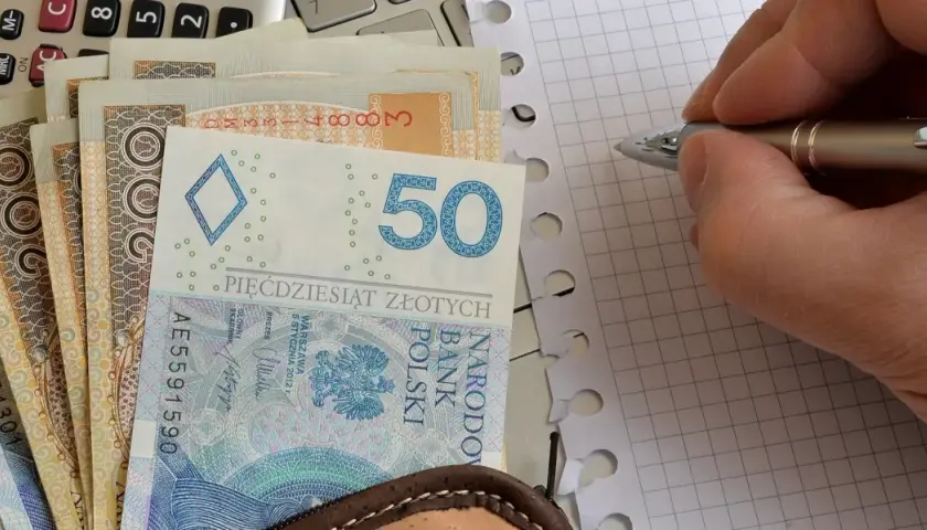 Zasiłek pielęgnacyjny to wsparcie dla osób potrzebujących. Na zdjęciu polskie banknoty, kalkulator i notatnik.