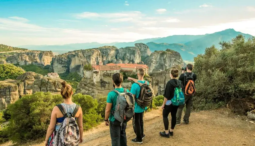 Hikers admire the stunning monasteries of Meteora, Greece, from a scenic viewpoint. The group enjoys a breathtaking vista during their hiking adventure.