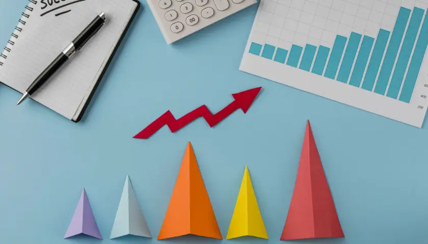 Notatnik z napisem "SUCCESS", kalkulator, wykres słupkowy i czerwona strzałka w górę symbolizują udany marketing performance.