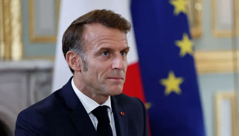 Emmanuel Macron na tle flagi Francji i UE. Czy we Francji jest ta sama godzina co w Polsce? Nie, jest godzina wcześniej.