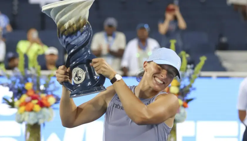 Iga Świątek triumfuje po wygranym finale, unosząc puchar.