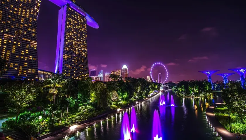 Widok nocny Singapuru z Marina Bay Sands, diabelskim młynem i podświetlanymi drzewami.