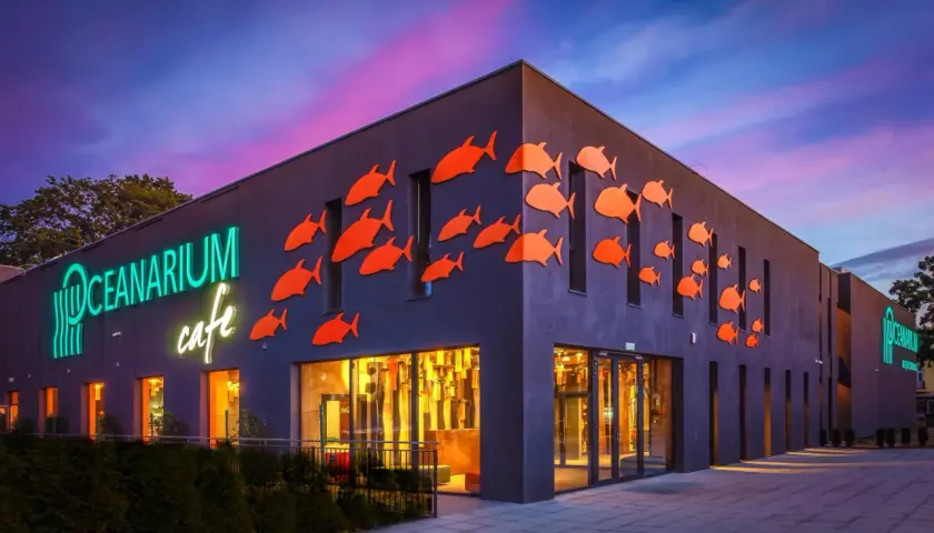 Oceanarium w Międzyzdrojach, z neonowym napisem i pomarańczowymi rybkami na fasadzie, to świetne miejsce na międzyzdrojskie atrakcje dla dzieci.