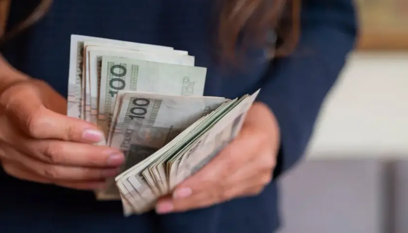 Dłonie liczą banknoty 100 zł. To portierka, która właśnie otrzymała zapłatę za swoją pracę.