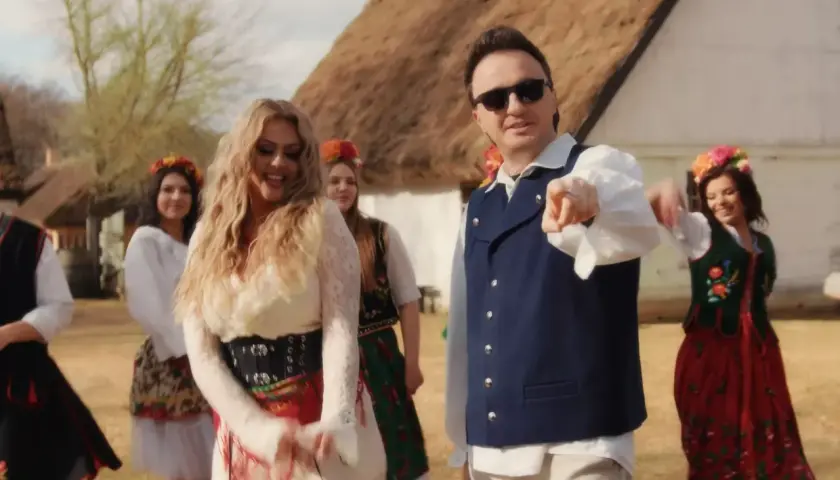 Patryk Pegza w stroju ludowym, otoczony tańczącymi kobietami. Ile ma lat? Trudno zgadnąć, ale wygląda na energicznego!
