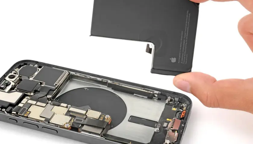 Wymiana baterii w iPhone 16. Dłoń trzyma nową baterię, gotową do montażu w otwartym telefonie.