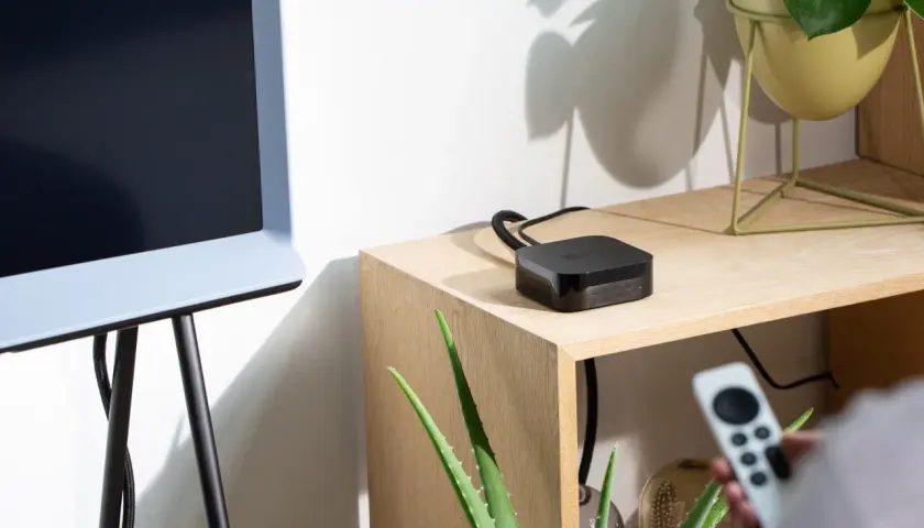 Ein Apple TV-Gerät liegt auf einem Holzregal neben einem alten Fernseher. So verbindest du deinen alten Fernseher mit dem Internet.