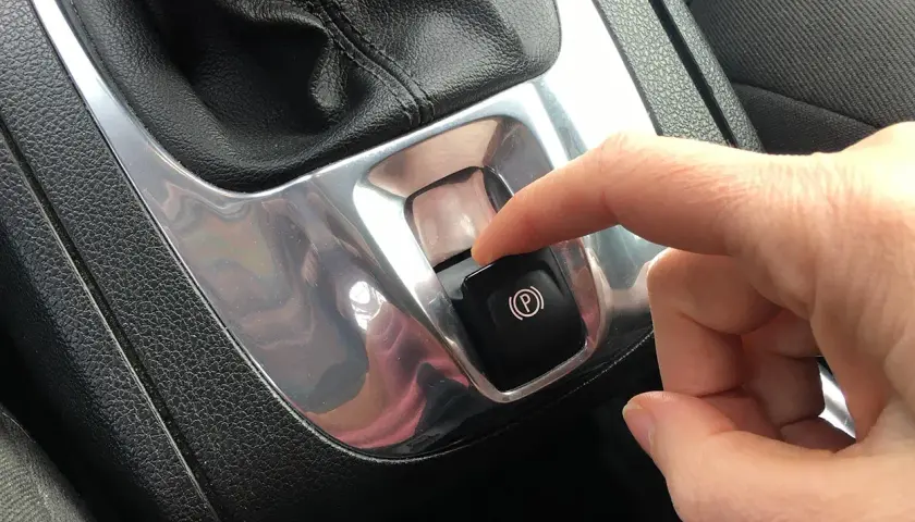 Dito, un dito preme il pulsante del freno a mano automatico, un gesto comune per parcheggiare in sicurezza.