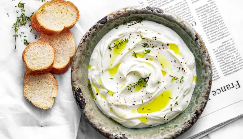 Labneh co to? Kremowy, gęsty serek z jogurtu, polany oliwą i posypany ziołami, podany z chrupiącym pieczywem.