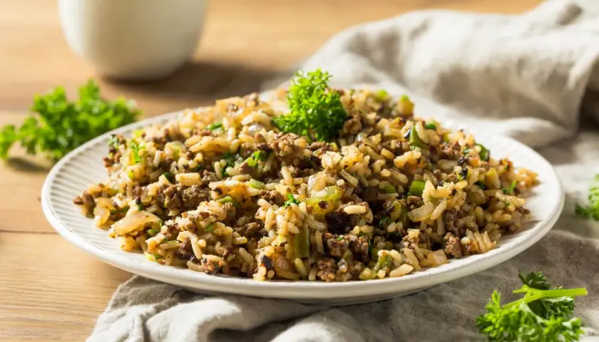 Plato de arroz integral con carne molida y verduras, decorado con perejil fresco.