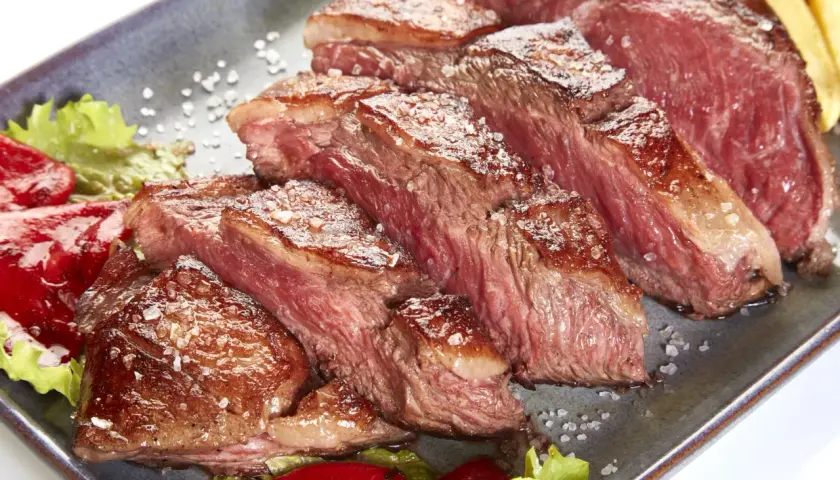 Tranches de picanha de veau juteuse, saupoudrées de gros sel, servies avec des poivrons rouges et de la laitue.