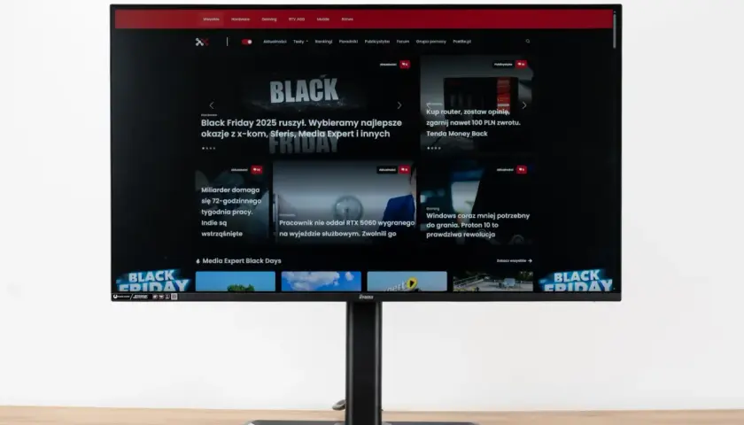 Monitor z widocznym na ekranie portalem Pcelite.pl, prezentującym artykuły o tematyce technologicznej, w tym promocje z okazji Black Friday. Test matrycy monitora jest kluczowy dla oceny jakości obrazu.
