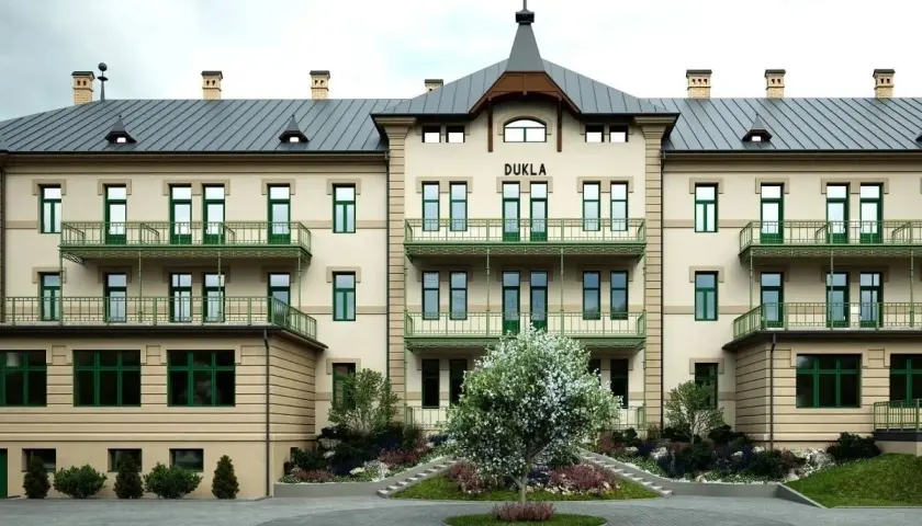 Elegancki budynek DUKLA z zielonymi balkonami i drzewkiem przed wejściem. Sprawdź bardejowskie termy cennik i zaplanuj relaks.